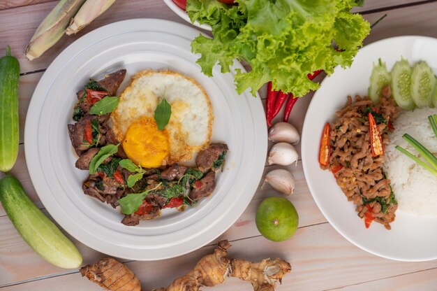 Stir fried basil liver with fried egg in a white plate.