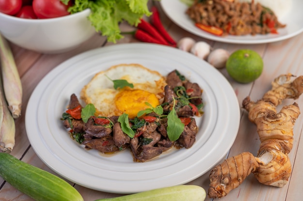 Stir fried basil liver with fried egg in a white plate.