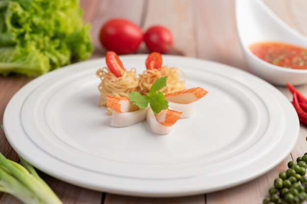 Stir-fried instant noodle with prawn and crab stick along  in a white dish.