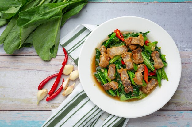 Stir fried kale, spicy crispy pork on wooden table Thai food concept.