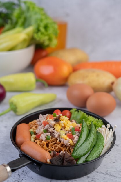 Stir-fried noodles with minced pork, edamame, tomatoes and mushrooms in a pan.