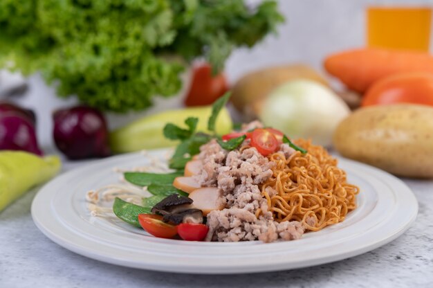 Stir-fried noodles with minced pork, edamame, tomatoes and mushrooms in a white plate.