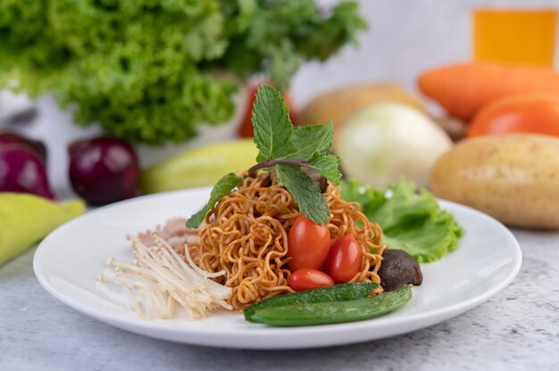 흰 접시에 다진 돼지 고기, 완두콩, 토마토 및 버섯으로 볶은 국수.