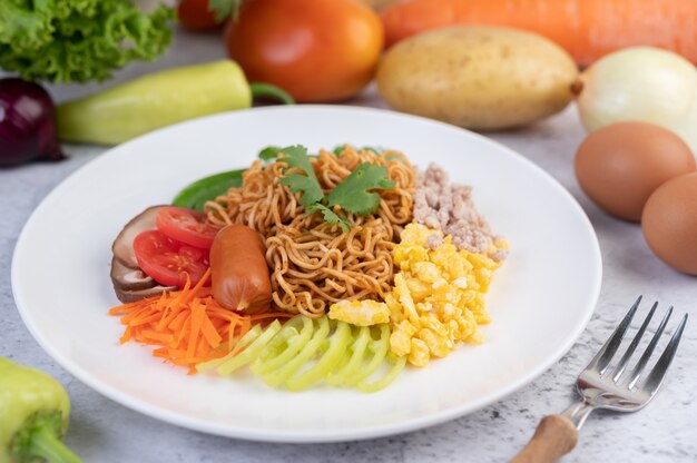 Stir-fried noodles with minced pork, edamame, tomatoes and mushrooms in a white plate.