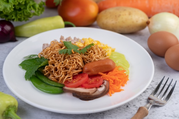 Stir-fried noodles with minced pork, edamame, tomatoes and mushrooms in a white plate.