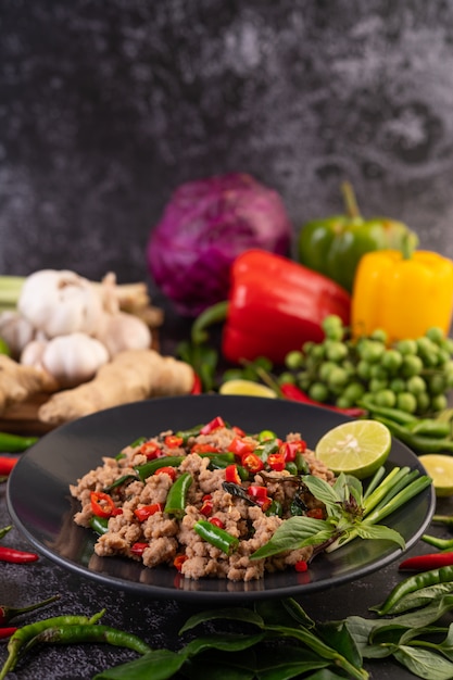 Stir-fried pork basil on banana leaves in a black dish.