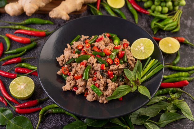 Stir-fried pork basil on banana leaves in a black dish.