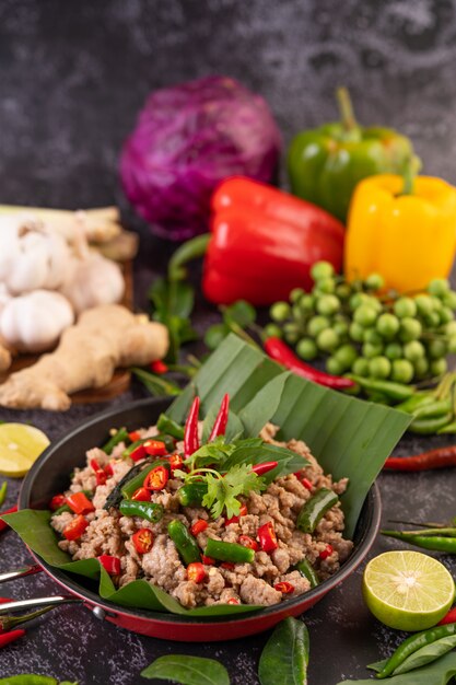 Stir-fried pork basil on banana leaves in a frying pan.