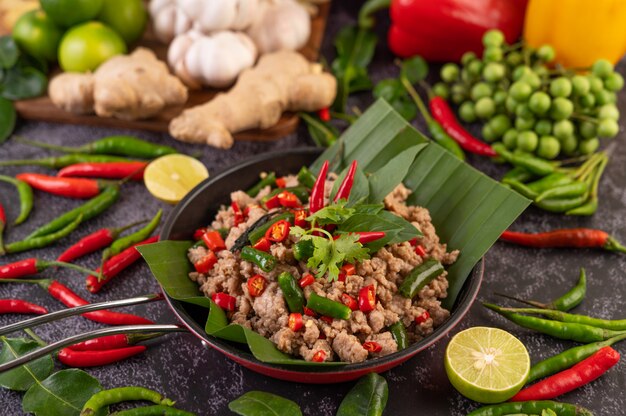 Stir-fried pork basil on banana leaves in a frying pan.