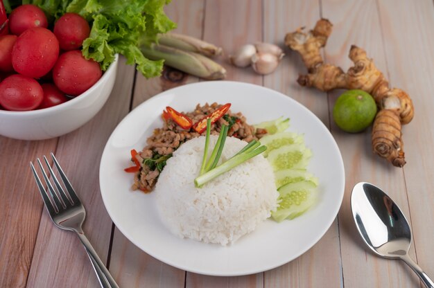 Stir fried pork with basil, fried egg in a white dish .