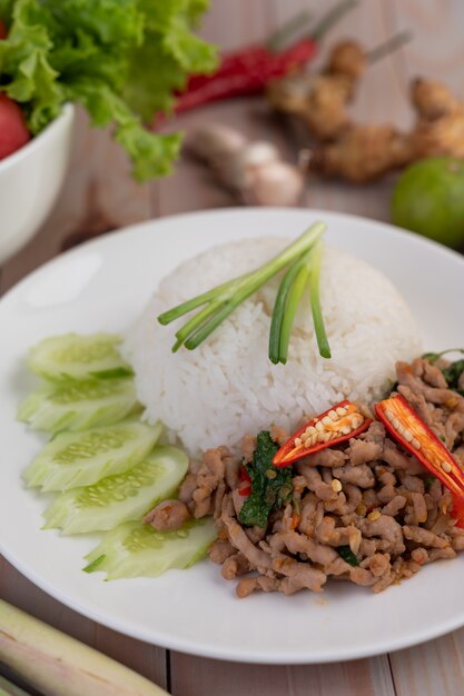 Stir fried pork with basil, fried egg in a white dish .