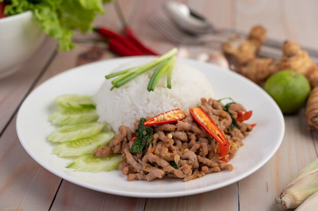 Stir fried pork with basil, fried egg in a white dish .