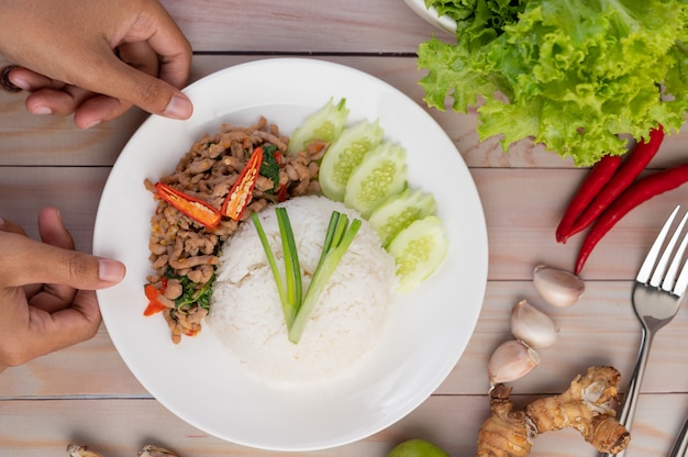 Stir fried pork with basil, fried egg in a white dish .