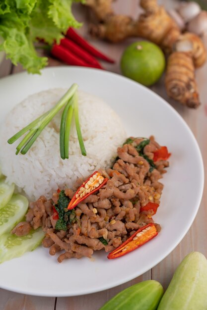 Stir fried pork with basil, fried egg in a white dish .