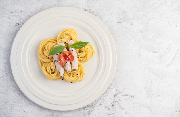Жареные спагетти и свинина, красиво оформленные в белой тарелке.