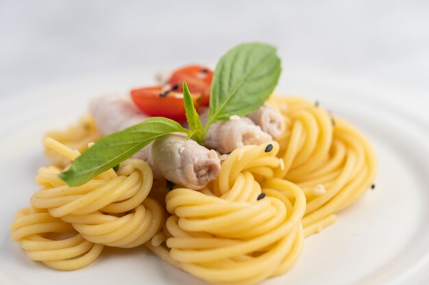 Жареные спагетти и свинина, красиво оформленные в белой тарелке.