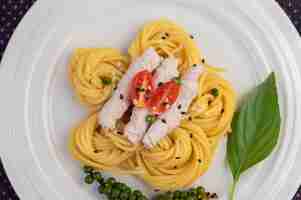 Foto gratuita spaghetti e maiale saltati in padella, splendidamente disposti in un piatto bianco.