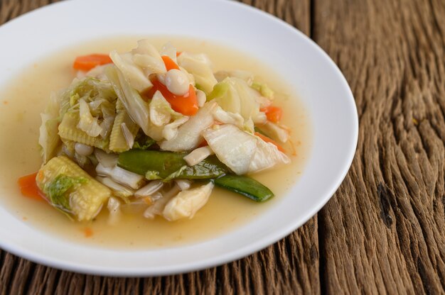 Stir fry mixed vegetables on a white plate on a wooden table.