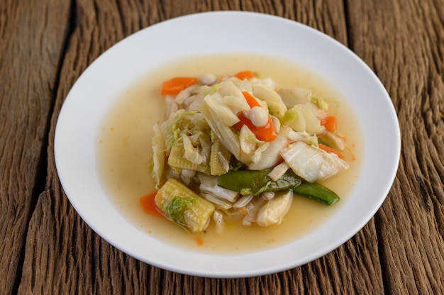 Free photo stir fry mixed vegetables on a white plate on a wooden table.