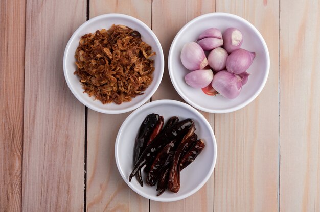 Stir fry onions, dried chilies and red onions in a white plate on a wooden floor.