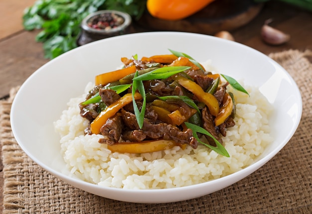 Free photo stir frying beef with sweet peppers, green beans and rice