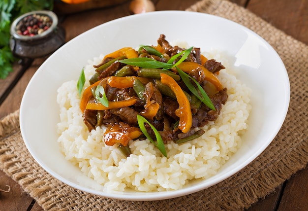 Stir frying beef with sweet peppers, green beans and rice