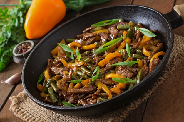 Free photo stir frying beef with sweet peppers and green beans