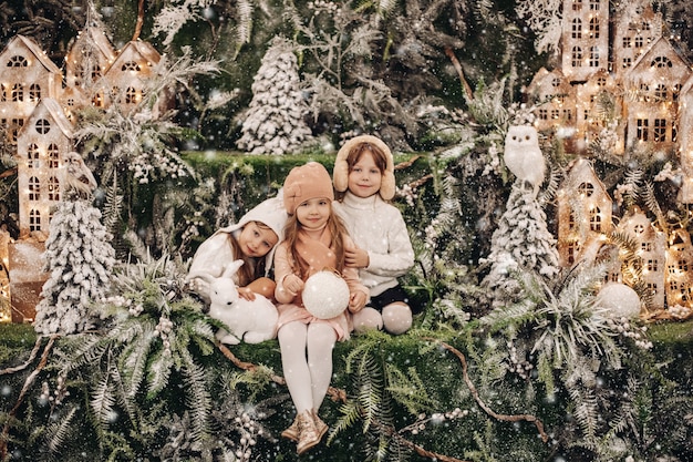 美しいクリスマスの装飾に囲まれて一緒に寄り添う愛らしい3人の姉妹のストックフォト。