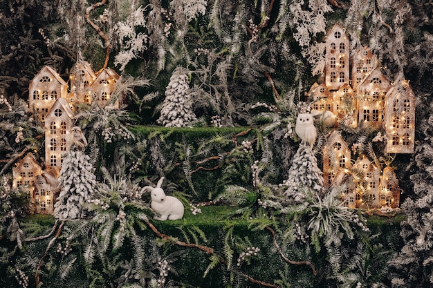Stock photo of beautiful handmade forest of fir trees and cardboard buildings illuminated with garlands and owl and rabbit decorative toys.