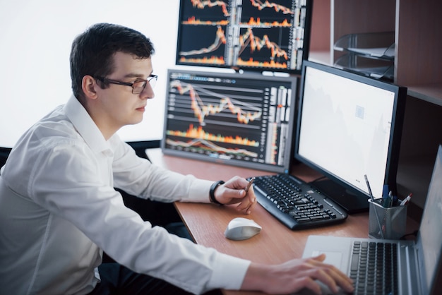 Stockbroker in shirt is working in a monitoring room with display screens. Stock Exchange Trading Forex Finance Graphic Concept. Businessmen trading stocks online