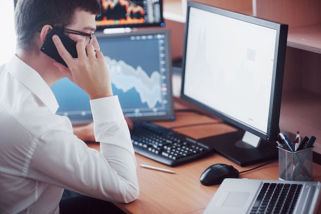 Stockbroker in shirt is working in a monitoring room with display screens. Stock Exchange Trading Forex Finance Graphic Concept. Businessmen trading stocks online