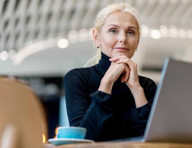 Stoic older business woman posing while working and having coffee