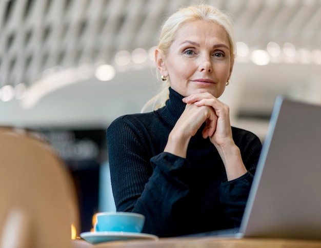 Stoic older business woman posing while working and having coffee