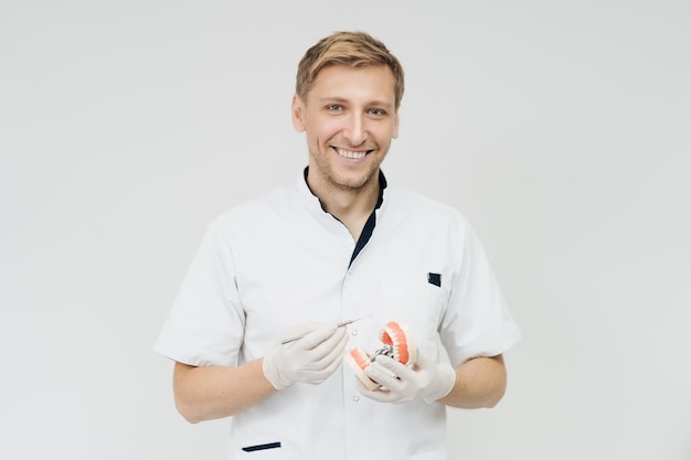 Stomatologist doctor explaining proper dental hygiene to patient holding sample of human jaw