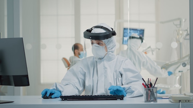 Free photo stomatology assistant sitting at desk using computer