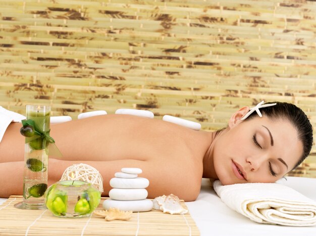 Stone massage for young woman at beauty spa salon. Recreation therapy.