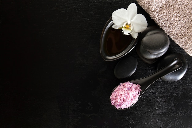 Stones with orchid and salt on black background