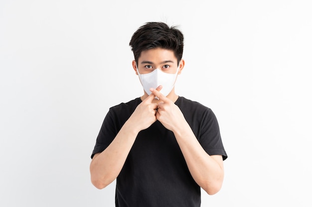 Stop civid-19, uomo asiatico che indossa la maschera per il viso mostra il gesto delle mani per fermare l'epidemia di virus corona