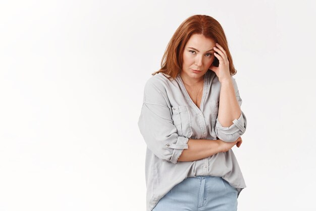 Stop it Irritated displeased annoyed redhead middleaged pressured woman touch temple look from under forehead scorn bothered cannot stand anymore displeased intense white background