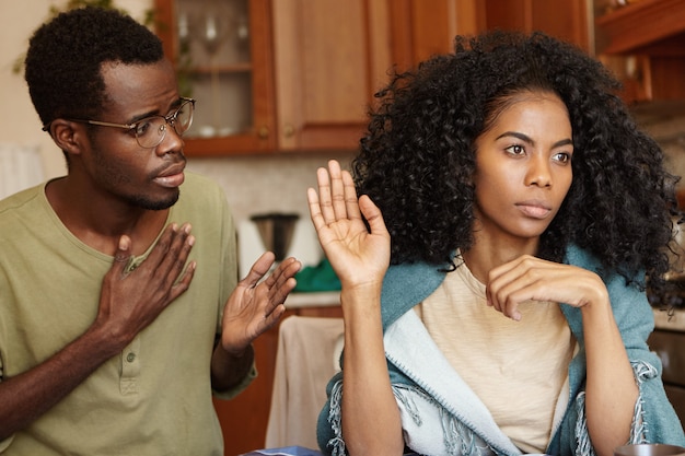 Stop lying to me. Angry beautiful Afro-American woman feeling mad at her unfaithful husband, ignoring his excuses, not believing in lies. Young couple going through hard times in their relationships