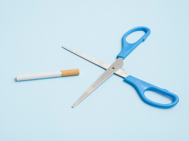 Stop smoking concept made with cigarette with scissor against blue backdrop