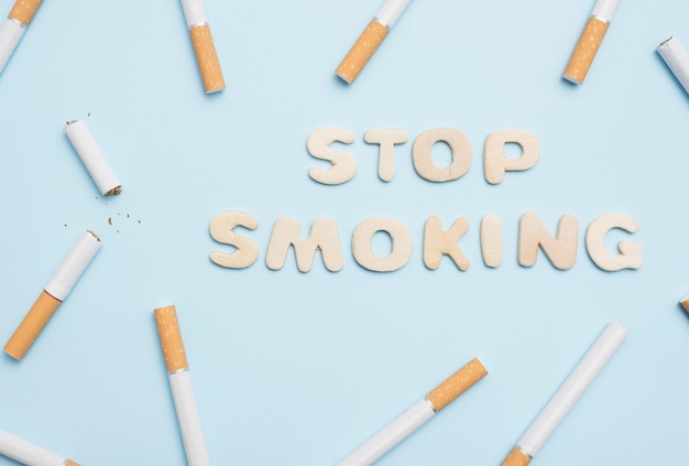 Stop smoking text with cigarettes on blue backdrop