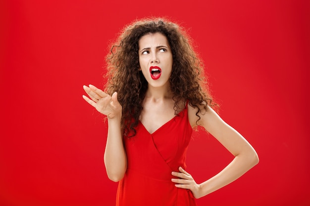 Free photo stop talking you making me sick. displeased and arrogant picky dark-haired woman with curly hairstyle saying blah-blah turning away from annoying person rolling eyes up and frowning from aversion.