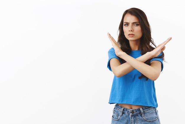 Free photo stop this immediately seriouslooking unsatisfied and unamused reluctant brunette woman making cross prohibition or forbid gesture dislike or disagree with person standing white background