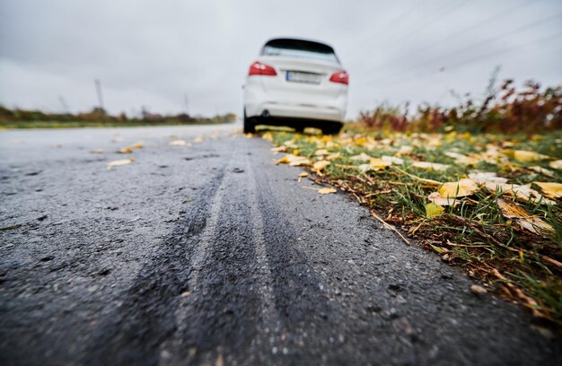 Stopped white car with punctured car tire on a roadside