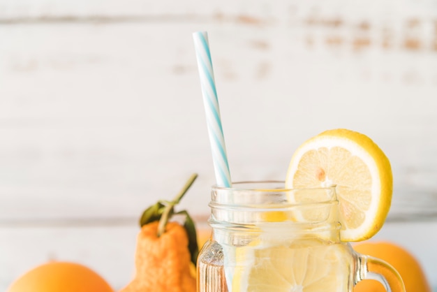 Straw in glass jar garnished with lemon slice 