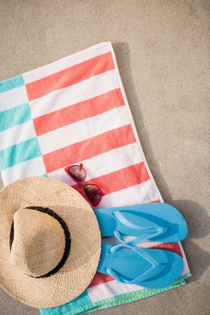 Соломенная шляпа, синий флип-флоп и солнцезащитные очки держали на пляже одеяло