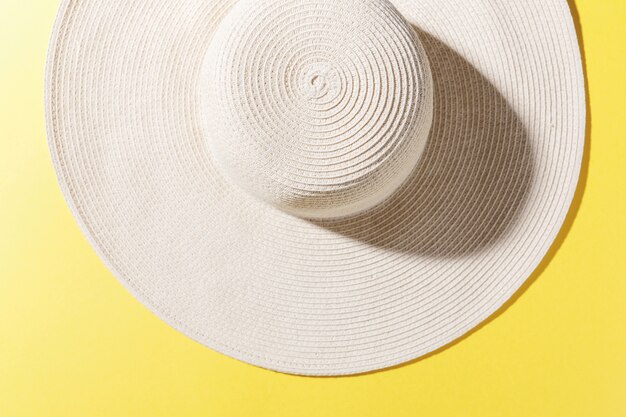 明るい黄色の日当たりの良い背景に麦わら帽子