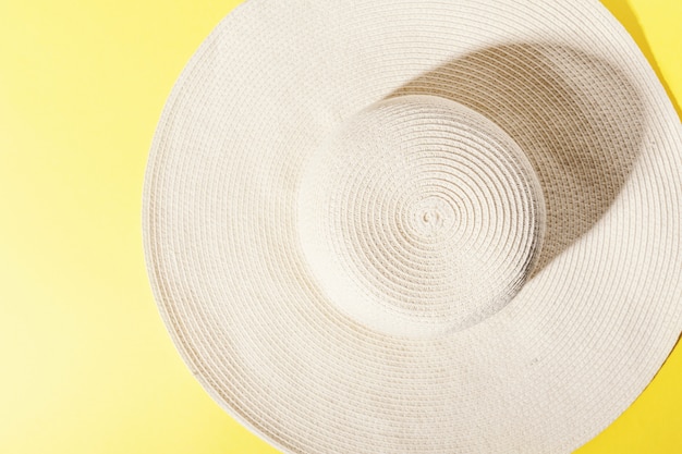 Straw hat on bright yellow sunny background