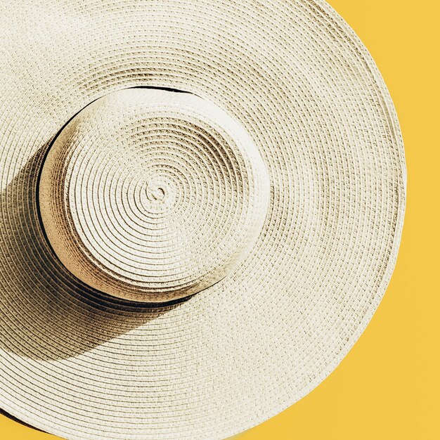 Straw hat on bright yellow sunny background